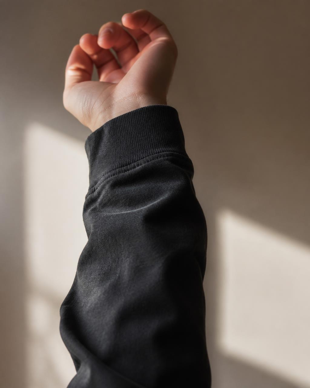 Close-up of a raised hand with the reminder printed down the right sleeve — “God's in control”